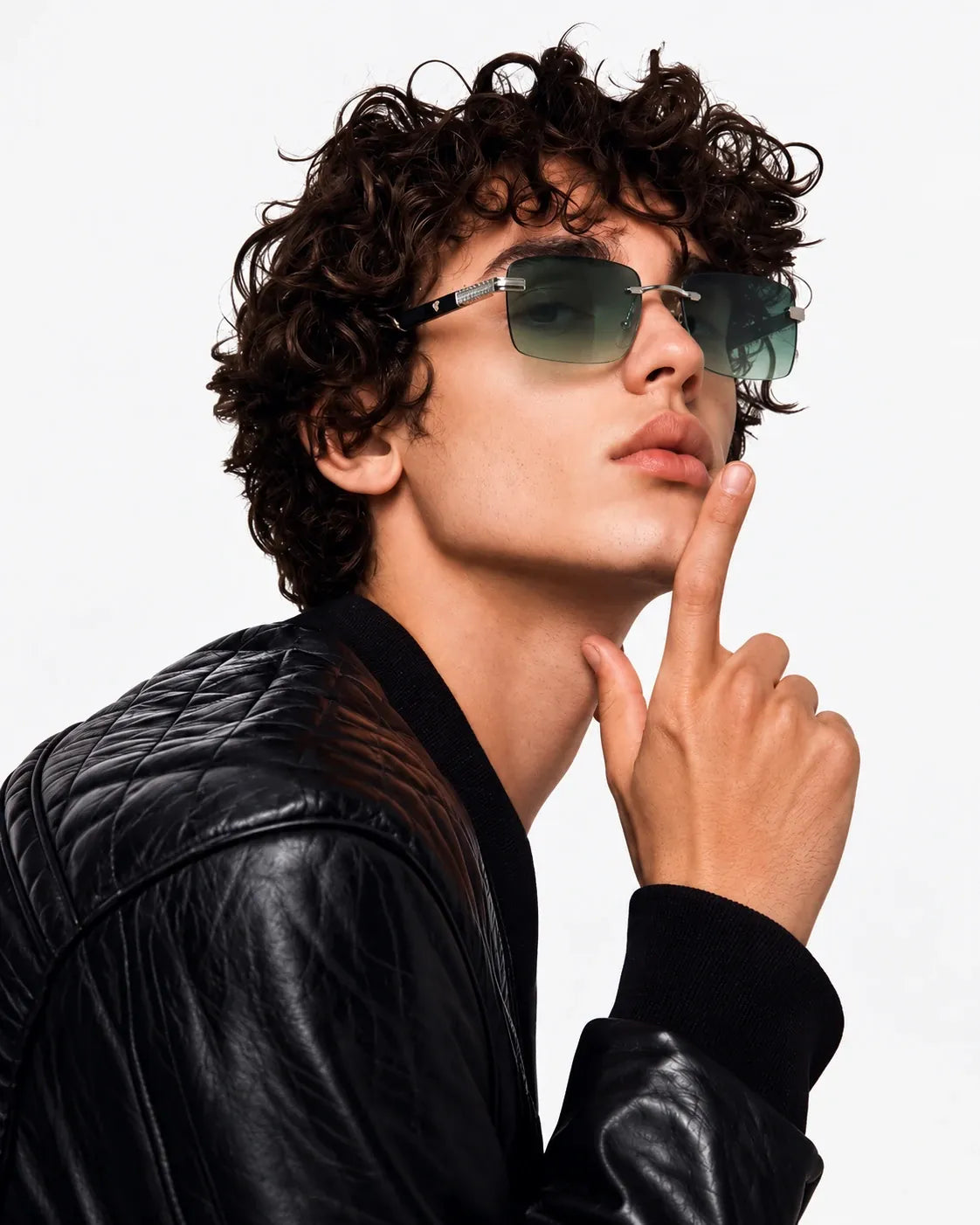 Curly-haired man in green-tint rimless sunglasses and a leather jacket